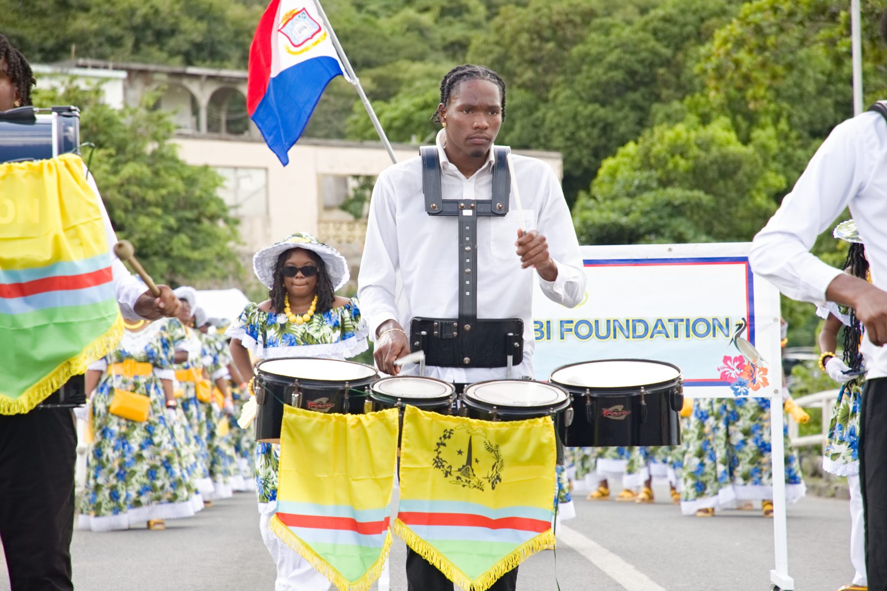Drummers leading a Sint Maarten cultural parade beneath the island flag