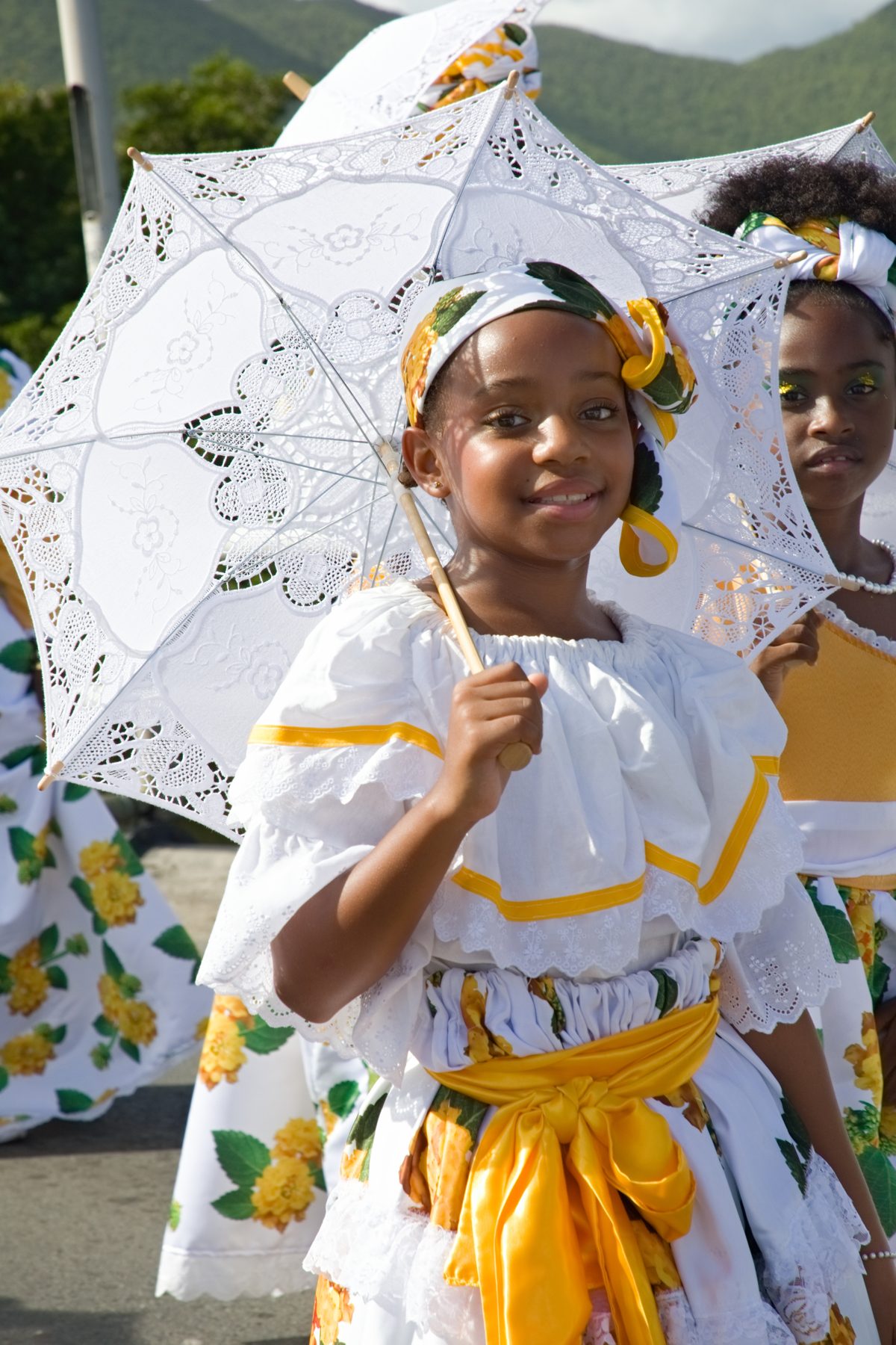 Young girls in traditional dress carrying lace parasols in the parade